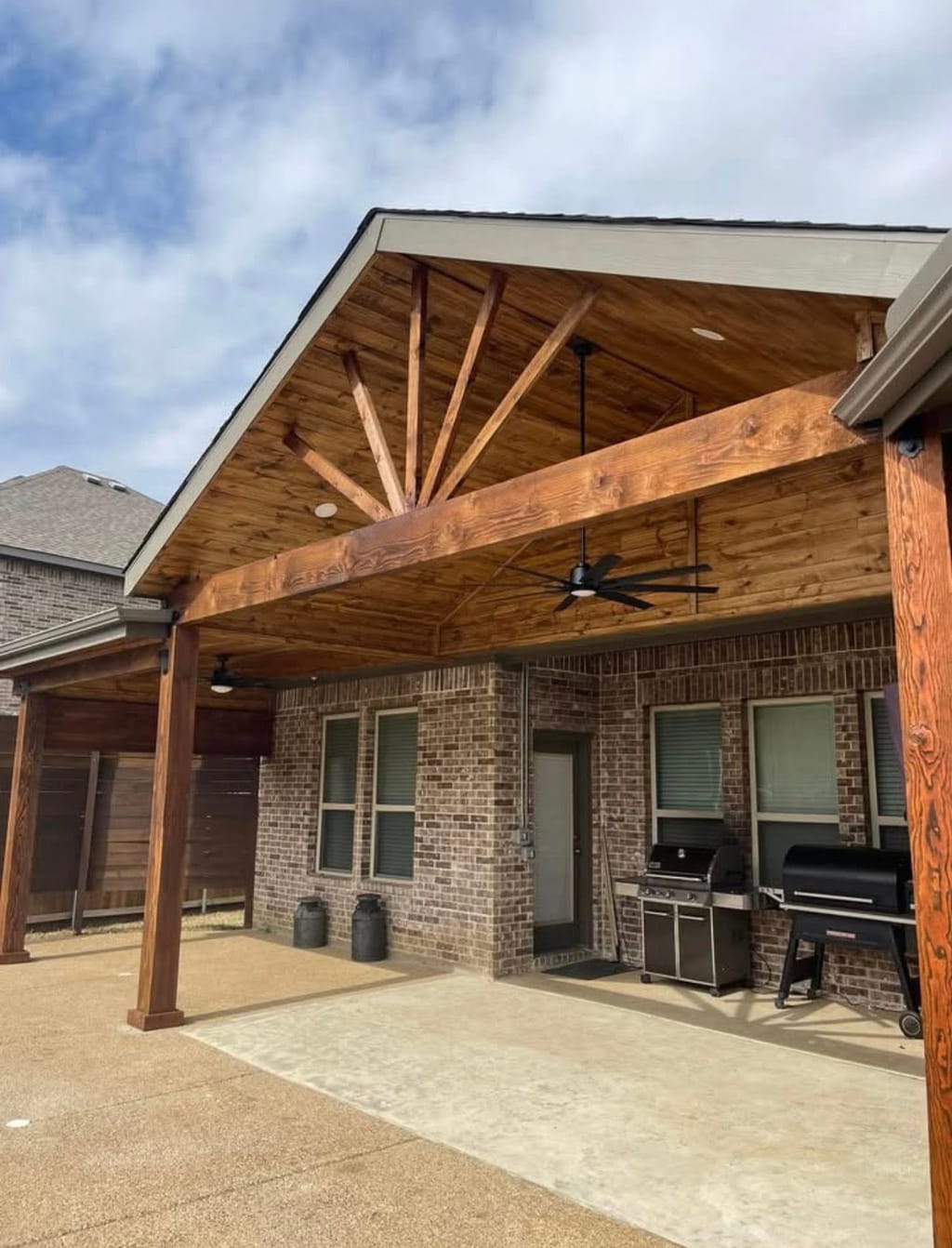 Gabled cedar patio cover with exposed rafters, ceiling fans and recessed lighting over a concrete patio in North Texas